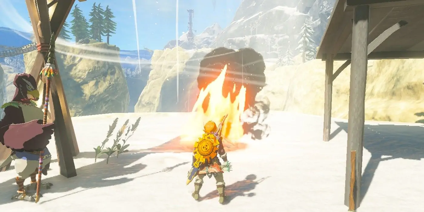 Link regarde l'explosion de flammes et de vent provoquée par la combustion d'une pomme de pin Hylian dans un feu de camp à l'extérieur du village de Rito dans The Legend of Zelda : Tears of the Kingdom.